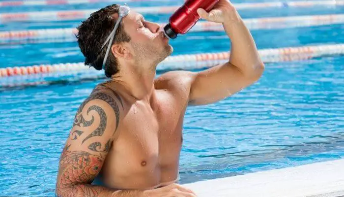 tattooed swimmer having a drink in the pool