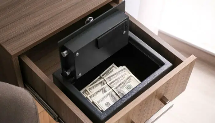 open draw with a small open safe containing money inside